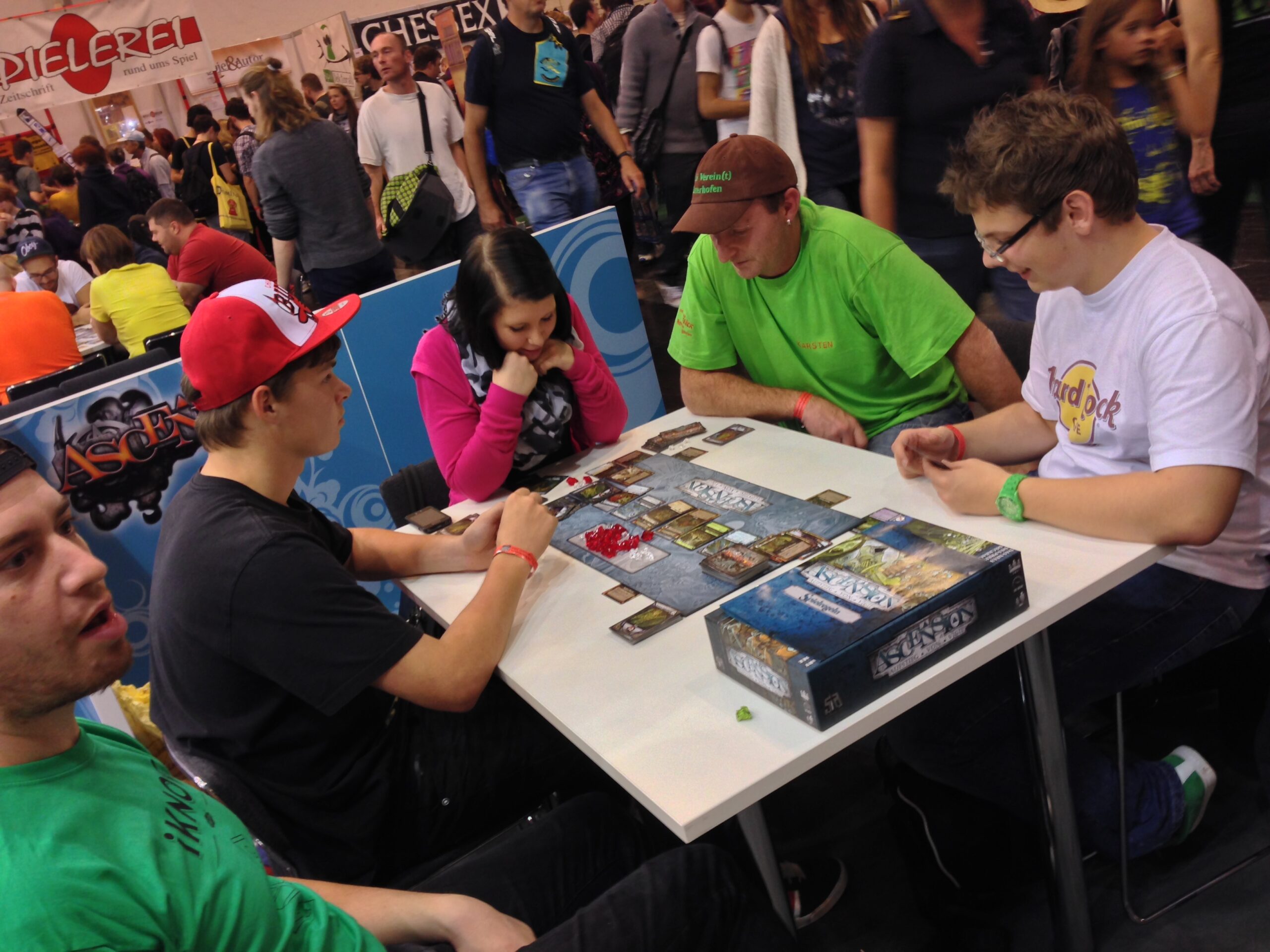 4 Menschen sitzen am Tischen und spielen das Spiel ASCENSIONS