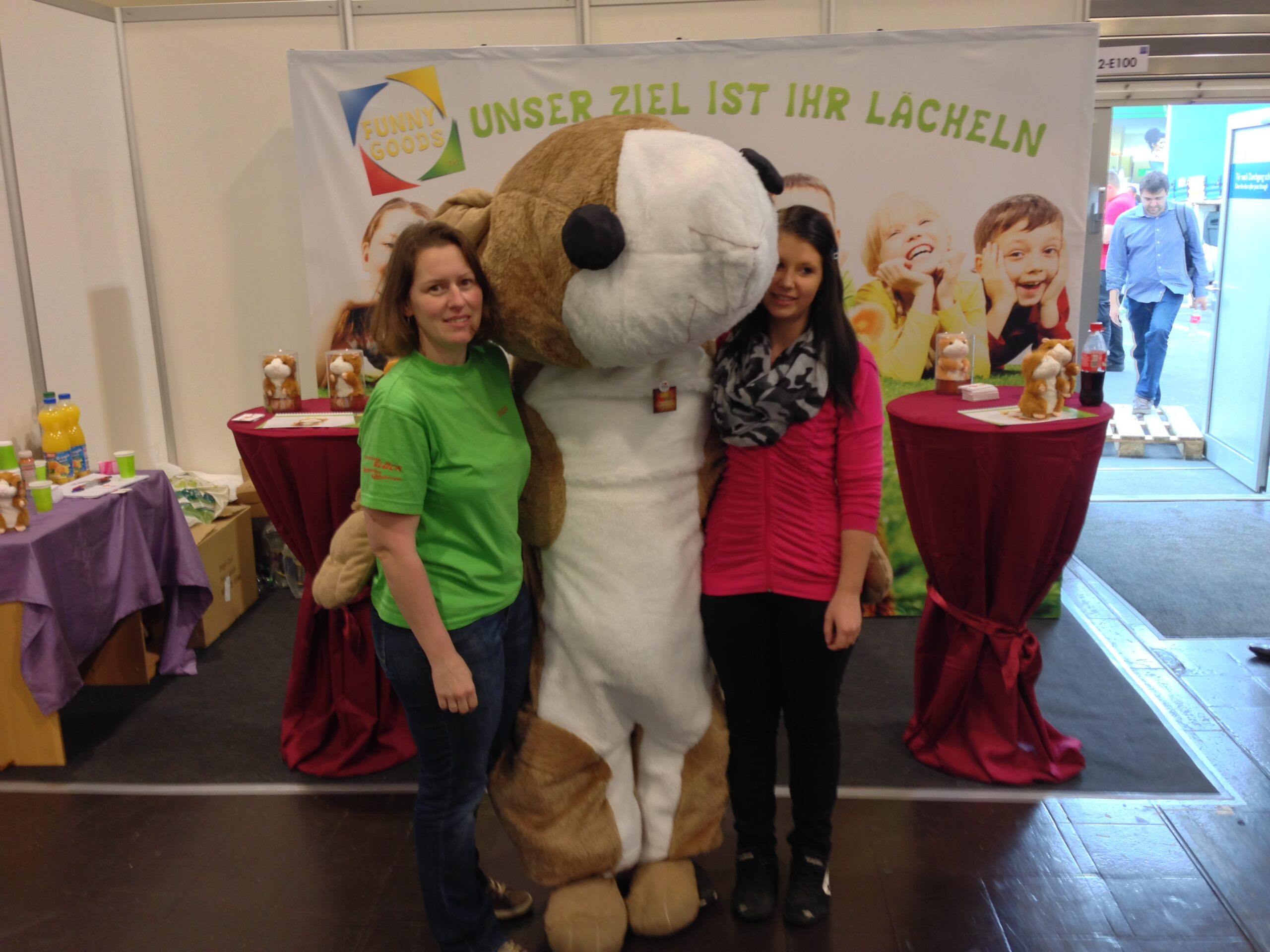 2 Frauen nehmen einen Menschen im Hamsterkostüm in die Mitte